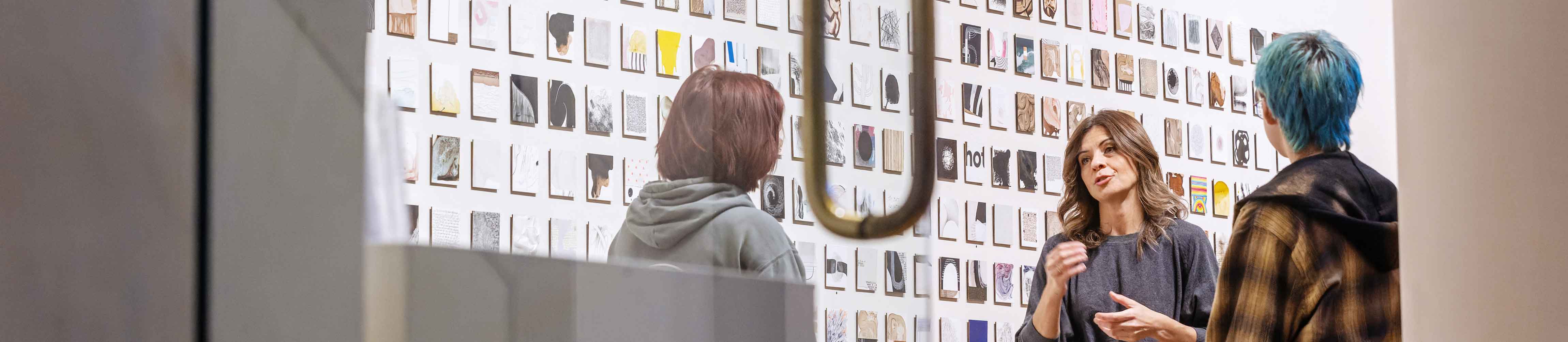 students talking on campus in a gallery